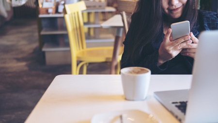 An Asian business woman holding and using smart phone and laptop in officeの写真素材
