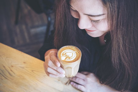 Top view image of Asian woman holding coffee cup and smelling hot coffee with feeling good in cafeの写真素材