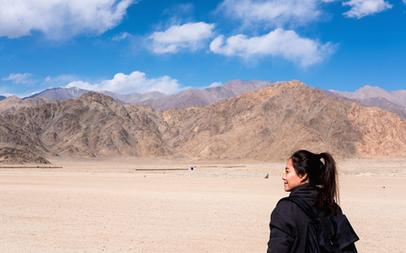 Portrait image of a beautiful Asian woman tourist standing in front of mountain and blue sky backgroundの写真素材