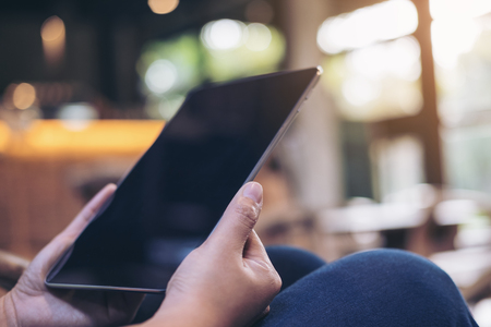 A woman's hands holding and using tablet pc with blur background in cafeの写真素材