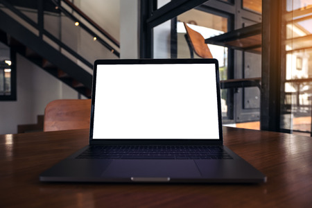 Mockup image of laptop with blank white screen on wooden table in modern loft cafeの写真素材
