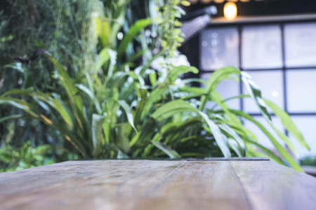 Close up image of a wooden table with blur bokeh of green nature backgroundの写真素材
