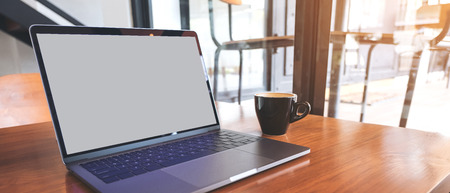 Mockup image of laptop with blank screen on wooden table near by window in modern cafeの写真素材