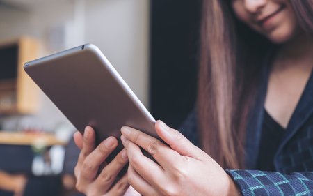 A woman's hands holding and using tablet pc with blur background in cafeの写真素材