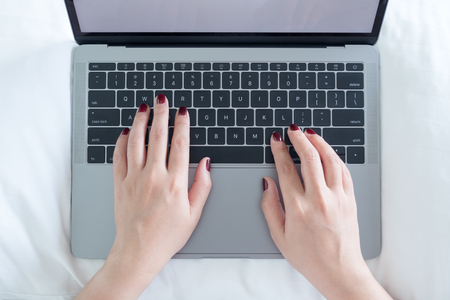 Top view closeup image of woman's hands typing on laptop on the bed in bedroomの写真素材