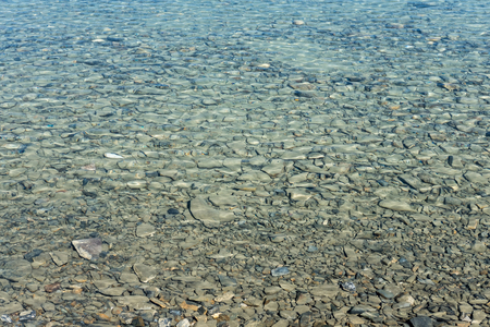 Closeup image of the stone under blue water in the lakeの写真素材