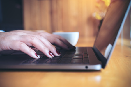 Closeup image of a business woman's hands working and typing on laptop keyboard on wooden tableの写真素材