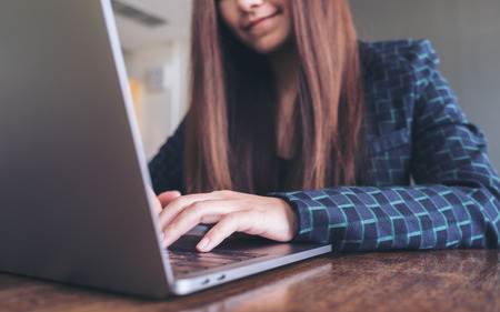 Closeup image of a business woman's hands working and typing on laptop keyboard on wooden tableの写真素材