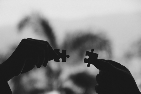 Black and white image of two hands holding a jigsaw puzzle with feeling love の写真素材