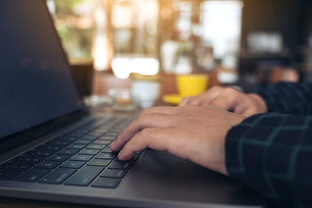 Closeup image of a business woman's hands working and typing on laptop keyboard on wooden tableの写真素材