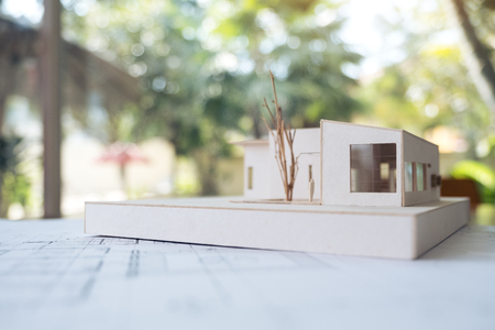 An architecture model with shop drawing paper and laptop on table in office with blur nature backgroundの写真素材