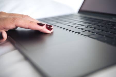 Closeup image of woman's hands using and touching on laptop keyboard with write backgroundの写真素材