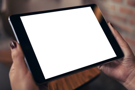 Mockup image of a woman holding black tablet pc with blank white desktop screen in cafeの写真素材