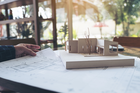 An architect working on an architecture model with shop drawing paper on tableの写真素材