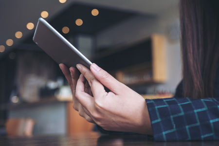 A woman's hands holding and using tablet pc with blur background in cafeの写真素材