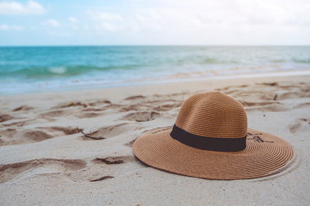 Closeup image of a sun hat or beach hat on the sand by the sea with blue sky backgroundの写真素材