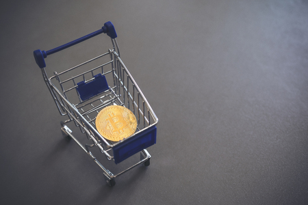 A golden bitcoin in a cart with gray color backgroundの写真素材