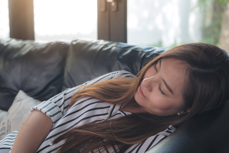 Closeup image of a beautiful asian woman taking a nap during daytime with feeling relaxedの写真素材