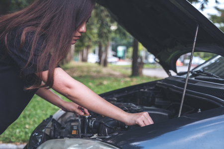 Woman try to fixing broken old car with outdoor backgroundの写真素材