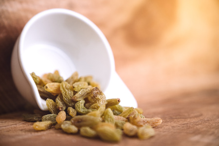 Closeup image of raisin in a white cup on wooden backgroundの写真素材