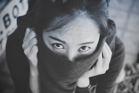 Black and white closeup image of a beautiful Asian woman looking and closing her mouth with clothの写真素材