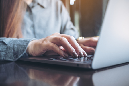 Closeup image of a business woman's hands working and typing on laptop keyboard on the tableの写真素材