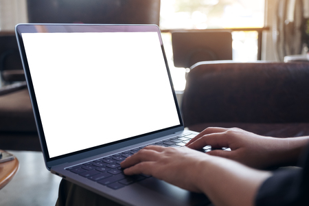 Mockup image of woman's hands using and typing on laptop with blank white desktop screen in cafeの写真素材