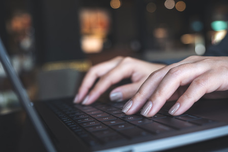 Closeup image of a business woman's hands working and typing on laptop keyboard on the tableの写真素材