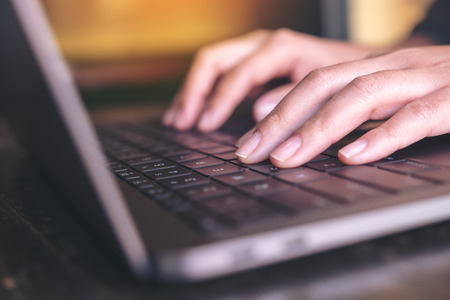 Closeup image of hands working and typing on laptop keyboard on the table