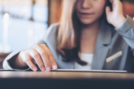 An Asian business woman using tablet with feeling stress and blur background in cafeの写真素材