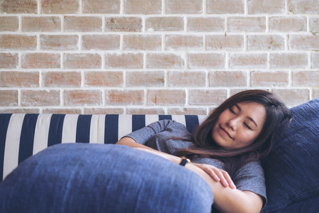 Image of an Asian woman sleeping in the sofa with feeling relax and comfortableの写真素材