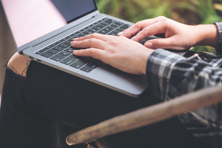 Closeup image of hands working , touching and typing on laptop keyboard with blur nature backgroundの写真素材