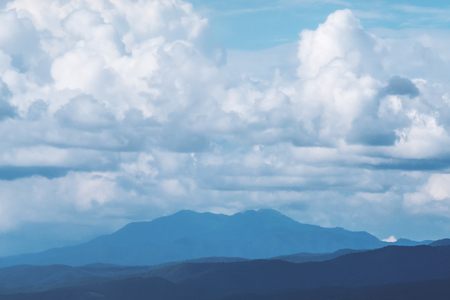 Green nature and mountain view with clouds in blue sky backgroundの写真素材