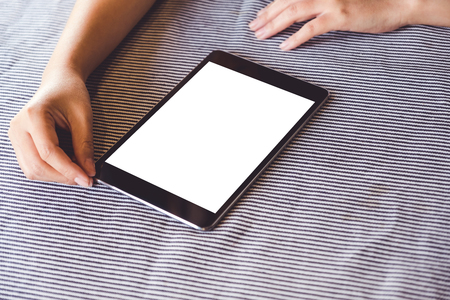 Mockup image of a person using black tablet pc with blank white desktop screen on the tableの写真素材