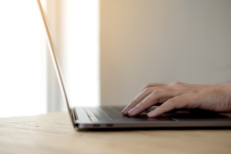 loseup image of hands working and typing on laptop keyboard on wooden tableの写真素材
