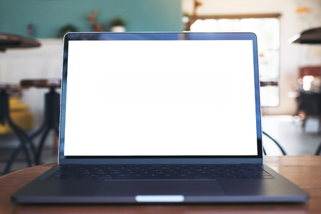 Mockup image of laptop with blank white desktop screen on wooden table in modern cafeの写真素材