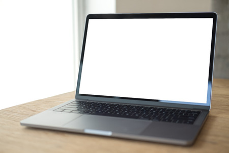 Mockup image of laptop with blank white desktop screen on wooden table in modern cafeの写真素材