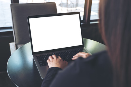 Mockup image of business woman using and typing on laptop with blank white screen on table in cafe