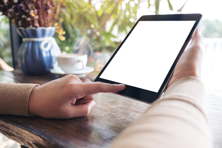 Mockup image of a woman holding black tablet pc with blank white desktop screen in cafeの写真素材