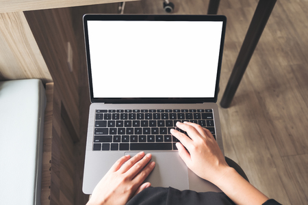 Top view mockup image of business woman using and typing on laptop with blank white desktop screen while sitting in officeの写真素材