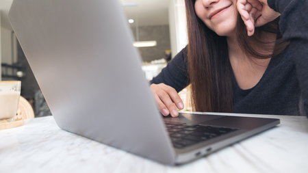 Closeup image of a woman using and looking at laptop with feeling happy in cafeの写真素材