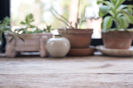 Closeup blur image of a wooden table with flowerpots in backgroundの写真素材