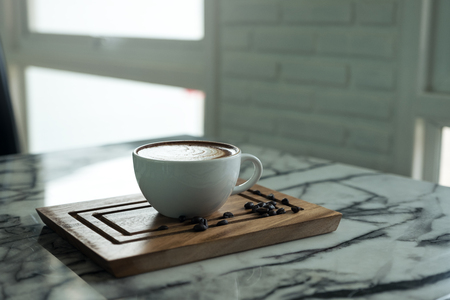 Closeup image of a cup of hot coffee and a wooden saucer on the table in cafe の写真素材