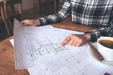 An architect working and pointing at shop drawing paper on table
