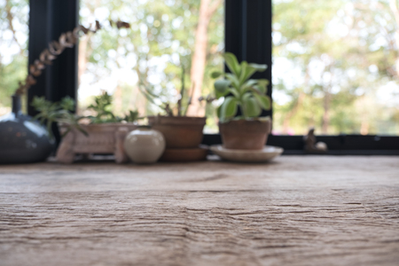Closeup blur image of a wooden table with flowerpots in backgroundの写真素材
