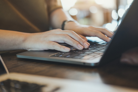 Closeup image of hands working and typing on laptop keyboard on table with blur backgroundの写真素材