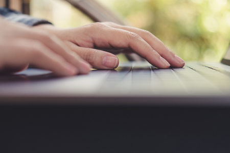 Closeup image of hands working , touching and typing on laptop keyboard with blur nature backgroundの写真素材