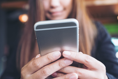 Closeup image of a woman holding , using and looking at smart phone の写真素材