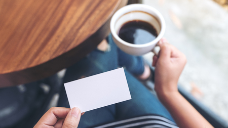 Hands holding an empty business card and coffee cupの写真素材