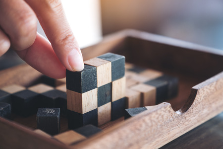 Closeup image of people playing and building wooden puzzle game